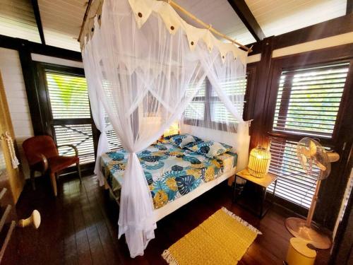 a bedroom with a bed with a canopy and windows at VILLA COCO ROSE in Les Anses-dʼArlets