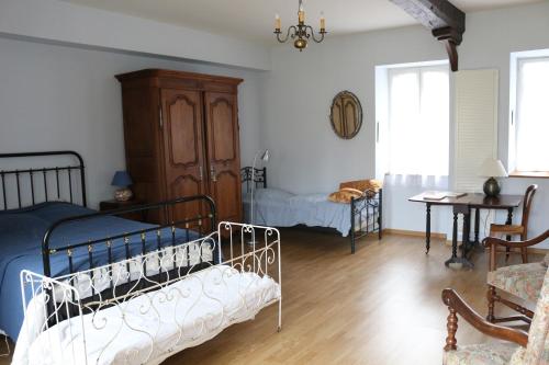 1 dormitorio con 2 camas, mesa y escritorio en Chez Célestine, en Souvigny