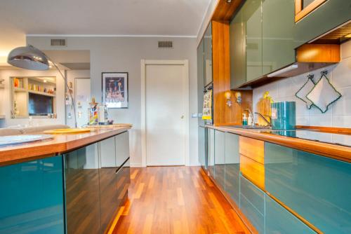cocina grande con armarios azules y suelo de madera en Casa di Bibi colorato elegante bilo vicino al Naviglio Martesana per 4 en Vimodrone