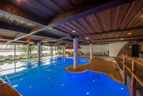 a large swimming pool with blue water in a building at Hotel Slovan in Vysoke Tatry - Tatranska Lomnica.
