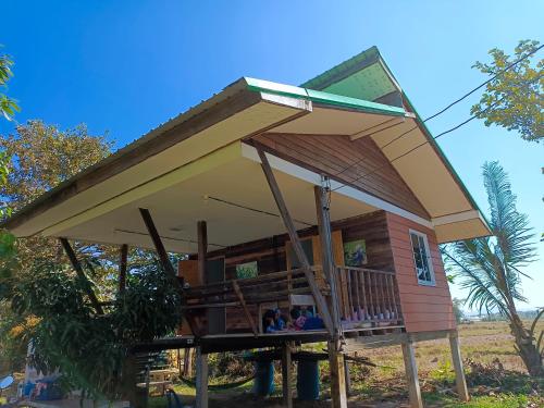 ein Haus auf Stelzen mit einem großen Dach in der Unterkunft Khunkorn Fishing Farm Stay in Ban Mae Kon