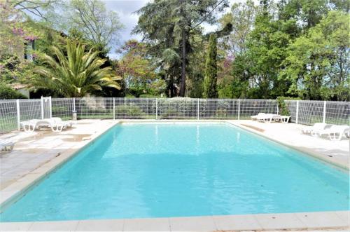 une grande piscine bleue avec des chaises et une clôture dans l'établissement LA CHAPELLE DU PRIEURE, à Alignan-du-Vent