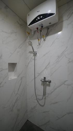 a shower in a bathroom with a white marble wall at Maharani Residence in Denpasar