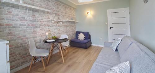 a living room with a table and a brick wall at Holiday Home SLAVIA NEW 408 z widokiem na morze in Międzyzdroje