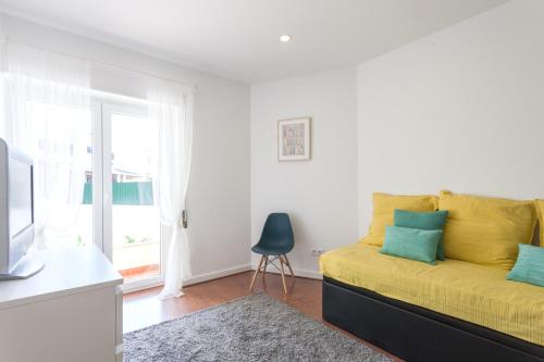 a bedroom with a yellow bed and a window at Grand Beach House Bliss, By TimeCooler in Carcavelos
