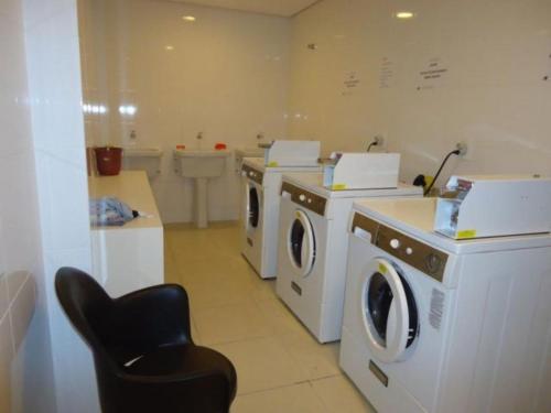 a laundry room with washing machines and a chair at Studio Moderno e Aconchegante in Curitiba