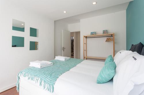 a bedroom with a white bed with blue pillows at Grand Beach House Bliss, By TimeCooler in Carcavelos