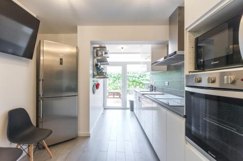 a kitchen with a stainless steel refrigerator and white cabinets at Grand Beach House Bliss, By TimeCooler in Carcavelos