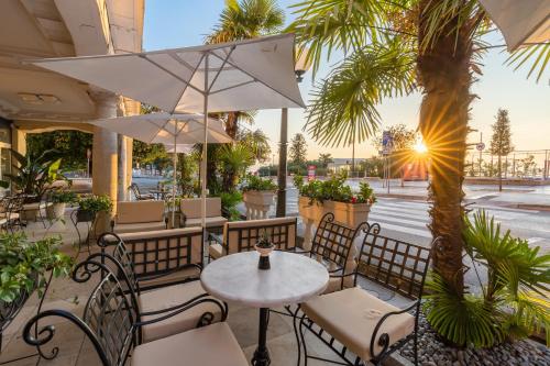 a patio with a table and chairs and a palm tree at Hotel Bellevue - Liburnia in Opatija