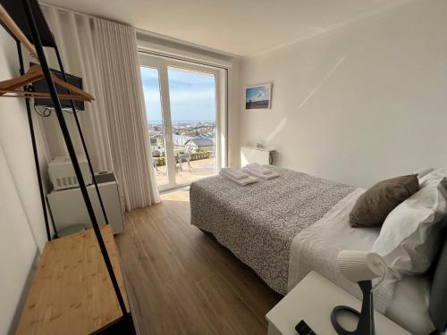 ein Schlafzimmer mit einem Bett und einem großen Fenster in der Unterkunft Alfazema Sunset House in Vila Nova de Gaia