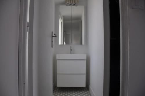 Baño blanco con lavabo y espejo en petit Gîte T2 des balcons d'Ancenis, en Ancenis