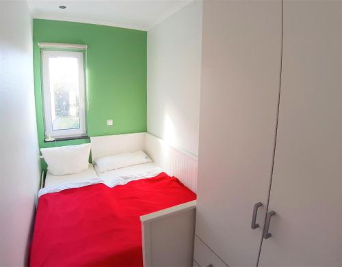 a small room with a red bed and a window at Strandbungalow Jette in Glowe