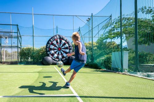 a boy hitting a soccer ball on a tennis court at Astir Odysseus Kos Resort and Spa in Tigaki