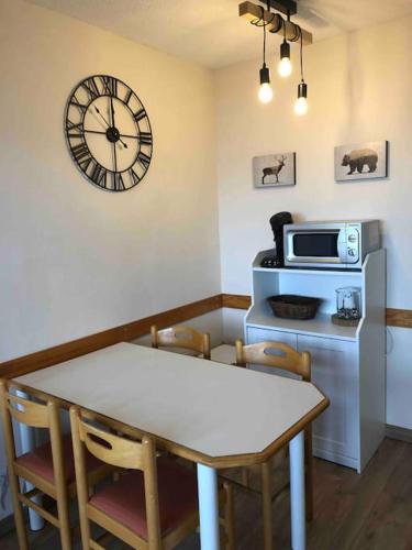 une cuisine avec une table et une horloge au mur dans l'établissement Studio 4 personnes proche des pistes, à La Plagne Tarentaise