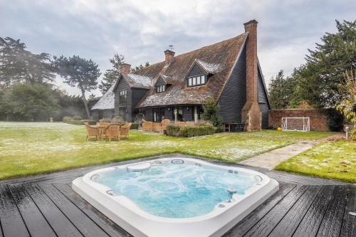 a hot tub on a deck in front of a house at Period Luxury Converted Barn Windsor/Maidenhead - Perfect for family groups in Taplow