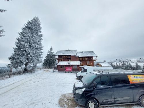 a suv parked in front of a house in the snow at Котеджі Цімбори in Yablunytsya