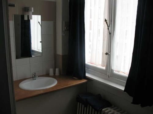 a bathroom with a sink and a mirror and a window at Logies Lucullus in Blankenberge