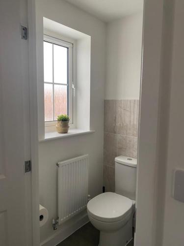 a white bathroom with a toilet and a window at Henry Blythe Gardens in Thame