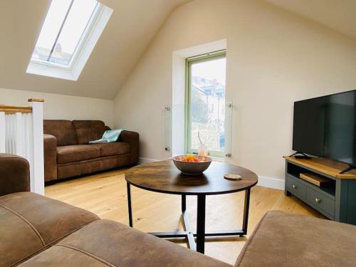 a living room with a couch and a table at Vindelis Cottage Chesil Beach in Portland