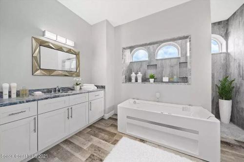 een witte badkamer met een bad en een spiegel bij Luxury Spanish-style vacation home! 