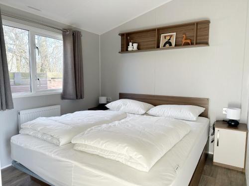 a white bed in a room with a window at Chalet 550 op Recreatiepark de Wielen in Sint Maarten