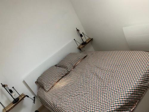 uma cama com duas almofadas num canto de um quarto em Une maison agréable pour se détendre em Saint-Quentin