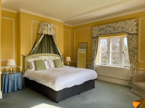 a bedroom with yellow walls and a bed with a canopy at Langrish House in Petersfield