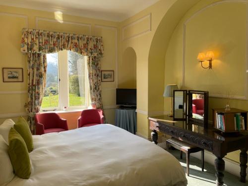 a bedroom with a bed and a desk and a window at Langrish House in Petersfield