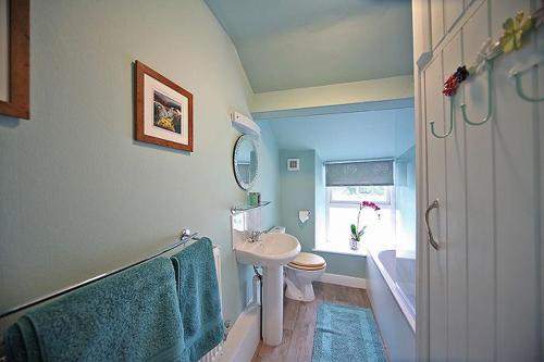 ein Badezimmer mit einem Waschbecken, einem WC und einem Spiegel in der Unterkunft 1 Kirkbeck Cottage Coniston in Coniston
