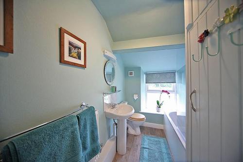 a bathroom with a sink and a toilet and a mirror at 1 Kirkbeck Cottage Coniston in Coniston