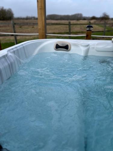 a hot tub filled with blue water with a bottle in it at Rife Lodges in Arundel