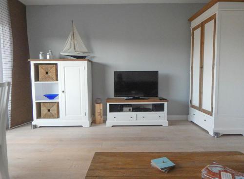 uma sala de estar com uma televisão e um armário branco em App. Saal em Wenningstedt