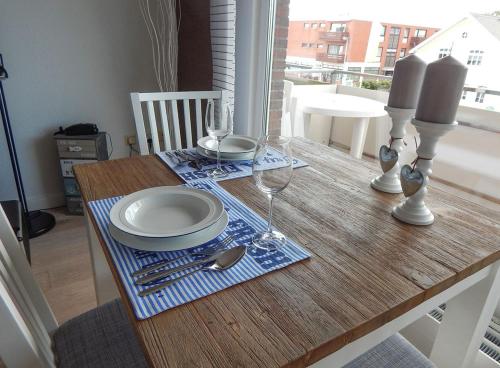 uma mesa de madeira com pratos e copos de vinho em App. Saal em Wenningstedt
