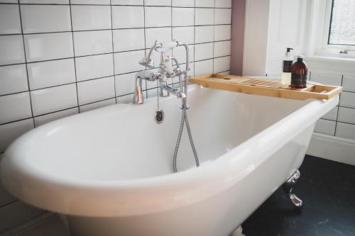 a white bath tub in a white tiled bathroom at Heatherfield House in Oban