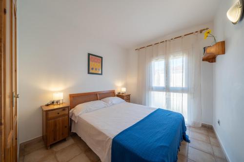 1 dormitorio con 1 cama con manta azul y ventana en Apartamento Sandy, en L'Escala