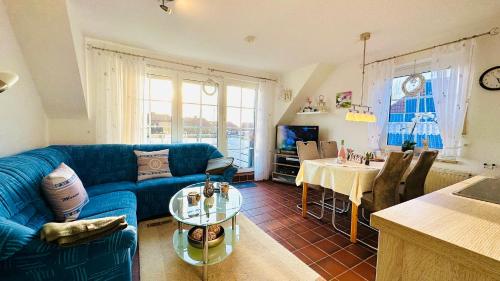 uma sala de estar com um sofá azul e uma mesa em Küstenliebe em Norden