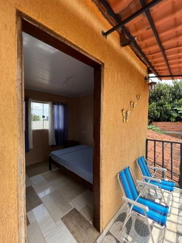 a bedroom with a bed and two chairs on a porch at Pousada Canela de Ema in Mateiros