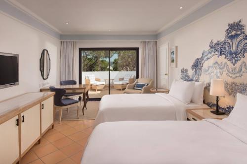 a hotel room with two beds and a living room at Pine Cliffs Hotel, a Luxury Collection Resort, Algarve in Albufeira