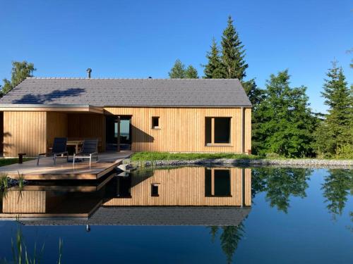 uma casa num lago com o seu reflexo na água em Ferienhäuser Gruber-List em Sankt Corona am Wechsel