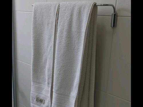 a white towel hanging on a towel rack in a shower at Apartamento Sol Poente in Ribeirão Preto
