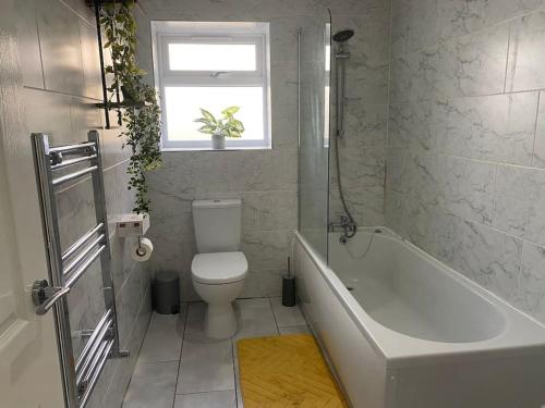 a bathroom with a toilet and a tub and a window at 10 St Andrews in Lytham St Annes