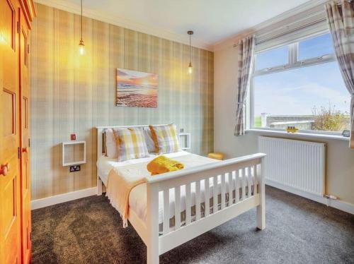 Sea View Cottage في Inverallochy: غرفة نوم بسرير ابيض ونافذة