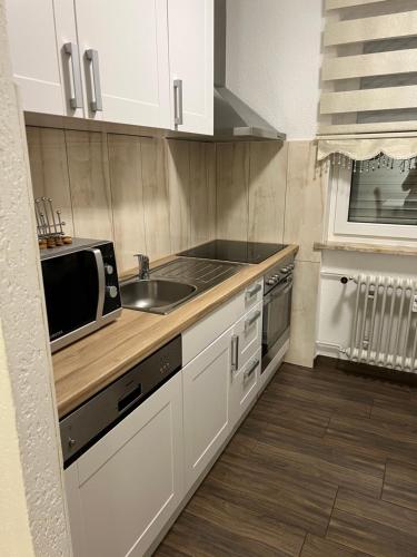 a kitchen with white cabinets and a sink and a microwave at O&V Apartment in Waldshut-Tiengen