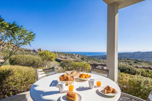 uma mesa com pratos de comida numa varanda com o oceano em Résidence Santa Monica em Bonifacio