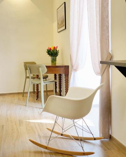 a living room with a white chair and a table at Le Nicchie - Ospitalità di Puglia in Bisceglie