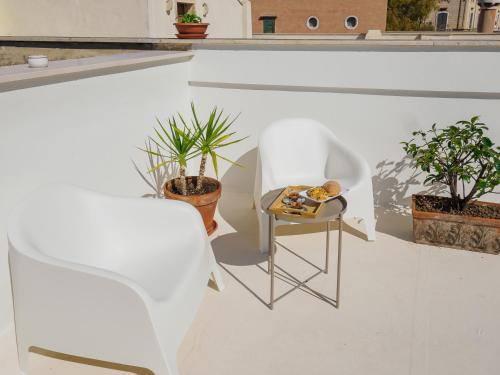 a white room with potted plants and a table at Le Nicchie - Ospitalità di Puglia in Bisceglie