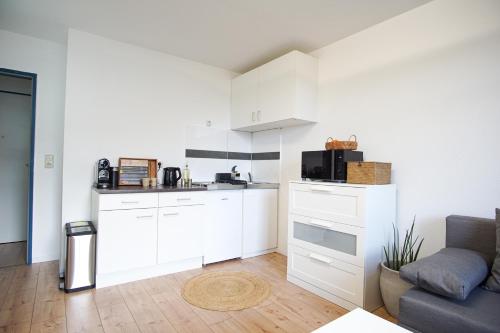 a kitchen with white cabinets and a couch in a room at Business Apartment - nah am Tierpark in Bielefeld