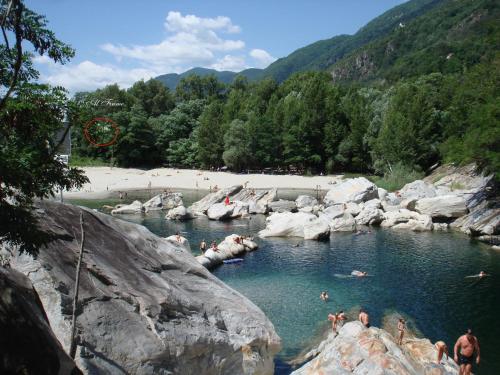 a group of people swimming in a river with rocks at Hotel Al Fiume in Tegna