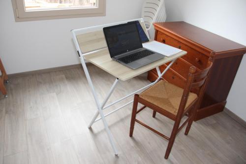 a laptop computer sitting on a desk next to a chair at ANCELLE TAILLAS RDC CHALET in Ancelle