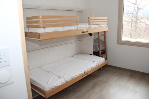 Ce dortoir comprend 2 lits superposés et une fenêtre. dans l'établissement ANCELLE TAILLAS RDC CHALET, à Ancelle